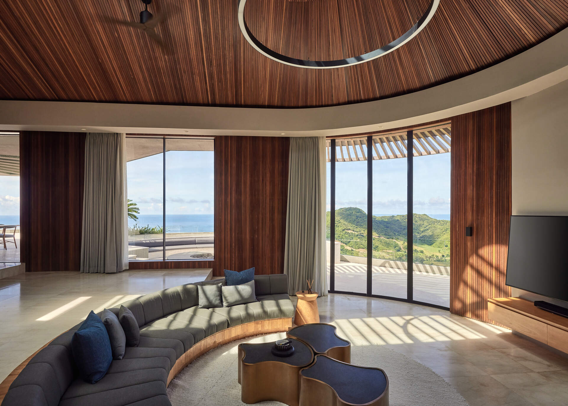 Curved built-in seating continues the home’s circular language, turning the TV room into an architectural feature.