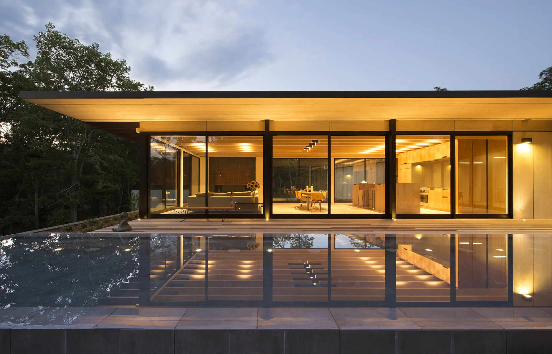 Light wood finishes and floor to ceiling windows create an interior that feels open, calm, and closely connected to the outdoors.