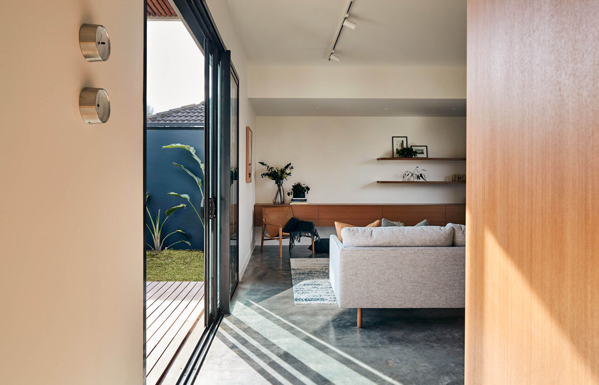 A cosy living room combines simple furniture, warm wood accents and polished concrete flooring.