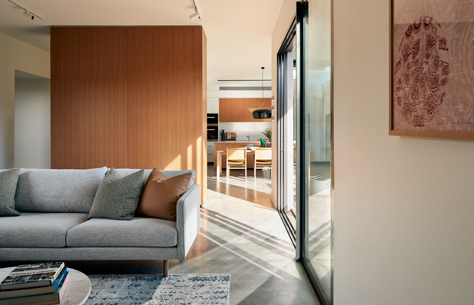 A cosy living room combines simple furniture, warm wood accents and polished concrete flooring.