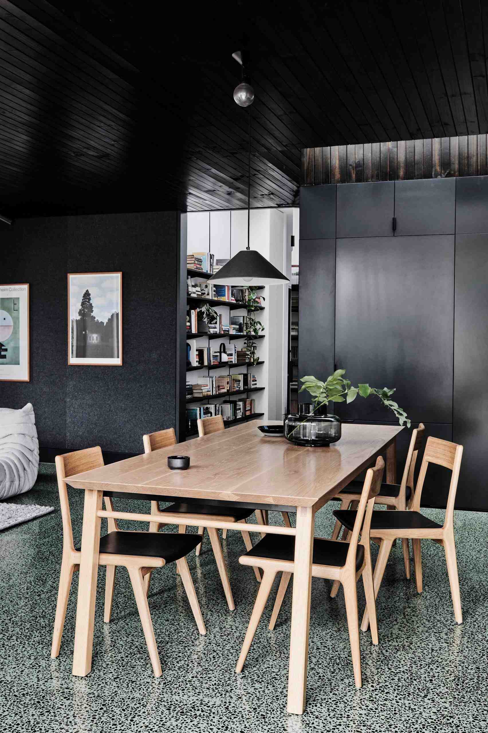 A warm wood dining space sits between living and kitchen, complete with shelving for a growing book collection.
