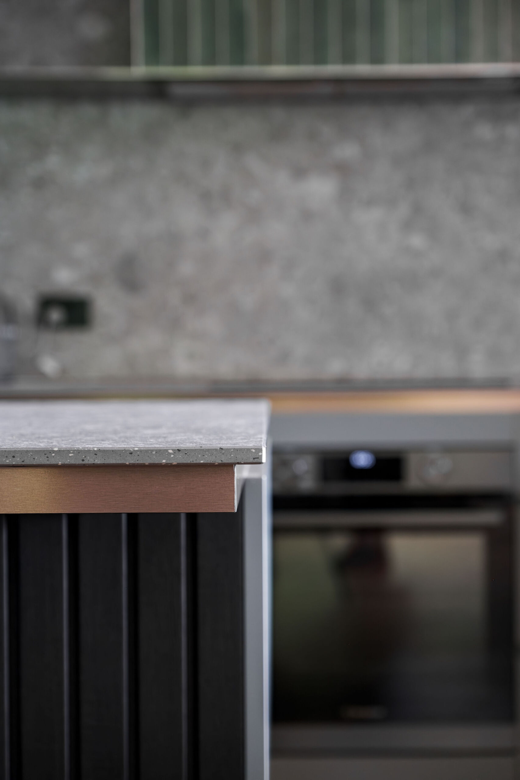 A nature inspired kitchen with stone countertops, green joinery, a tiled hood and soft eastern light flooding through a new window.