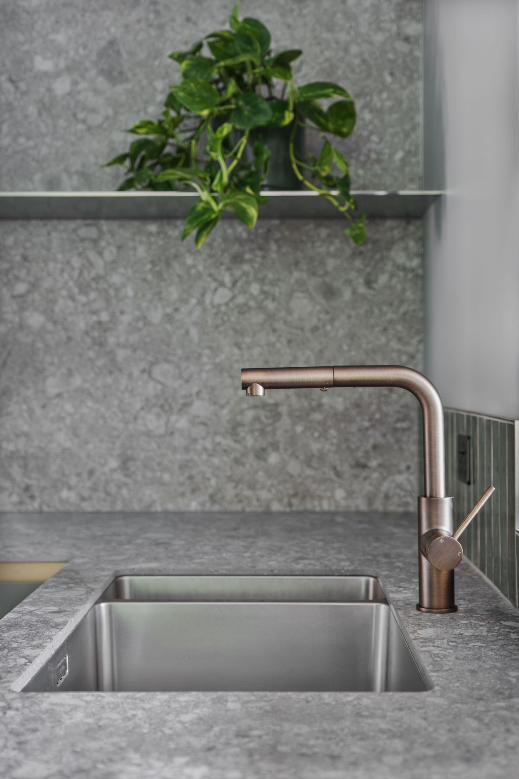 A nature inspired kitchen with stone countertops, green joinery, a tiled hood and soft eastern light flooding through a new window.