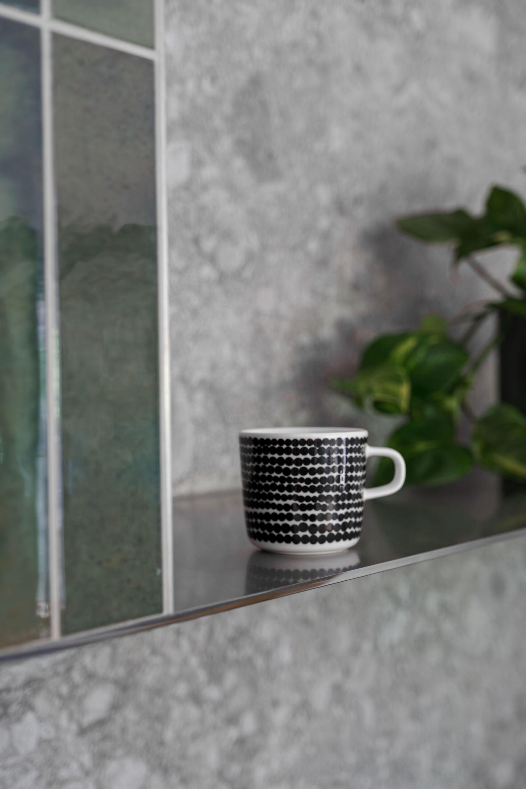 A nature inspired kitchen with stone countertops, green joinery, a tiled hood and soft eastern light flooding through a new window.