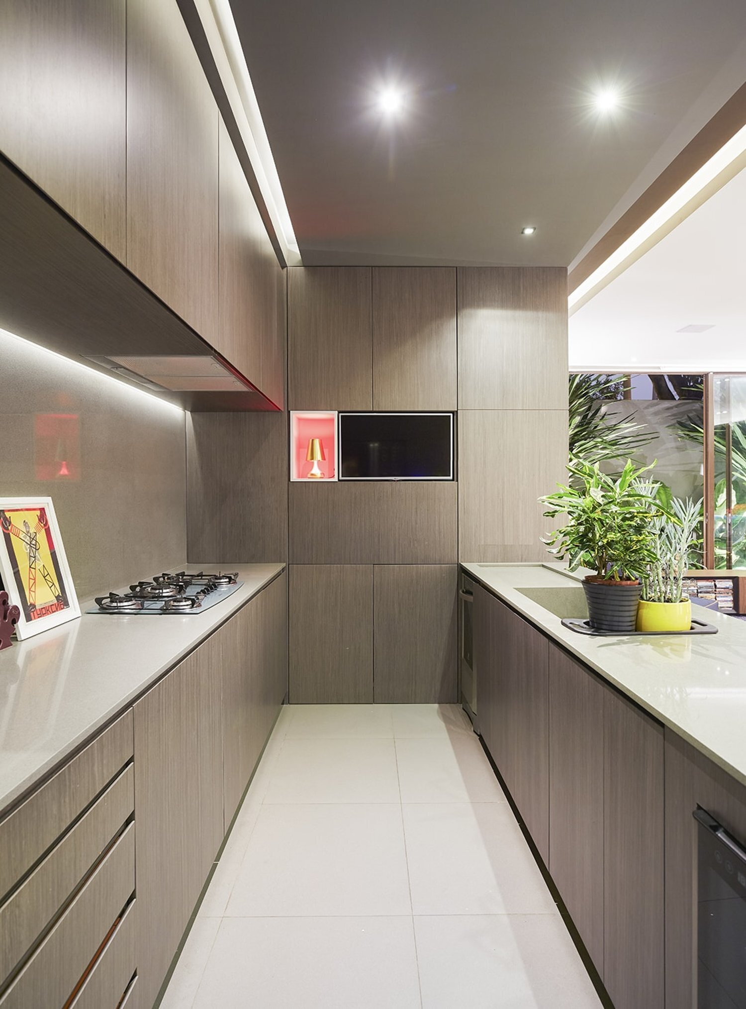 Rather than separating entry from everyday living, the house opens directly into its social areas. The kitchen sits prominently within this space, designed with minimalist, hardware free cabinetry that keeps the room visually calm.