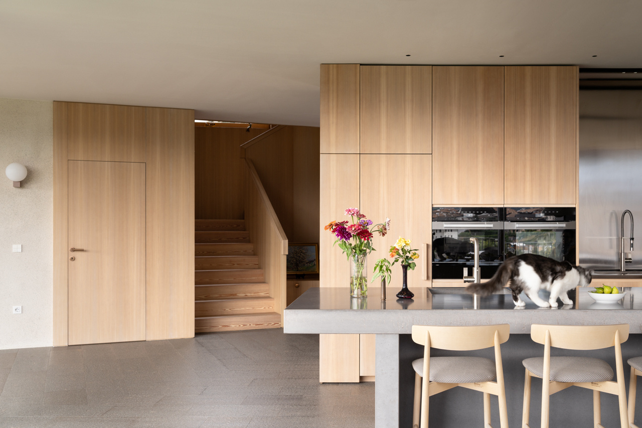 Larch wood, concrete, and stainless steel come together in a kitchen designed for shared cooking and everyday family life.