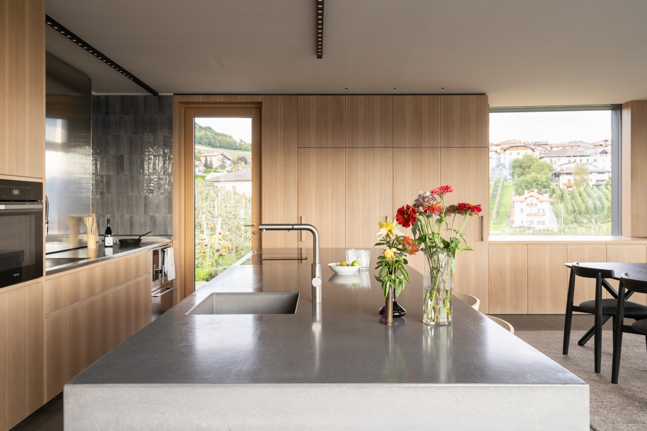 Larch wood, concrete, and stainless steel come together in a kitchen designed for shared cooking and everyday family life.