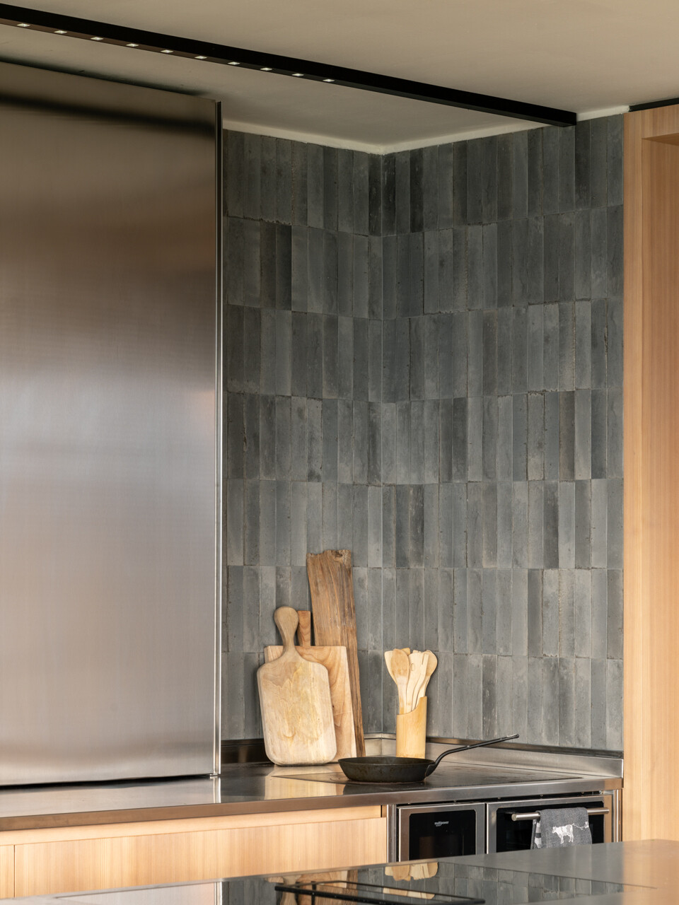 Larch wood, concrete, and stainless steel come together in a kitchen designed for shared cooking and everyday family life.