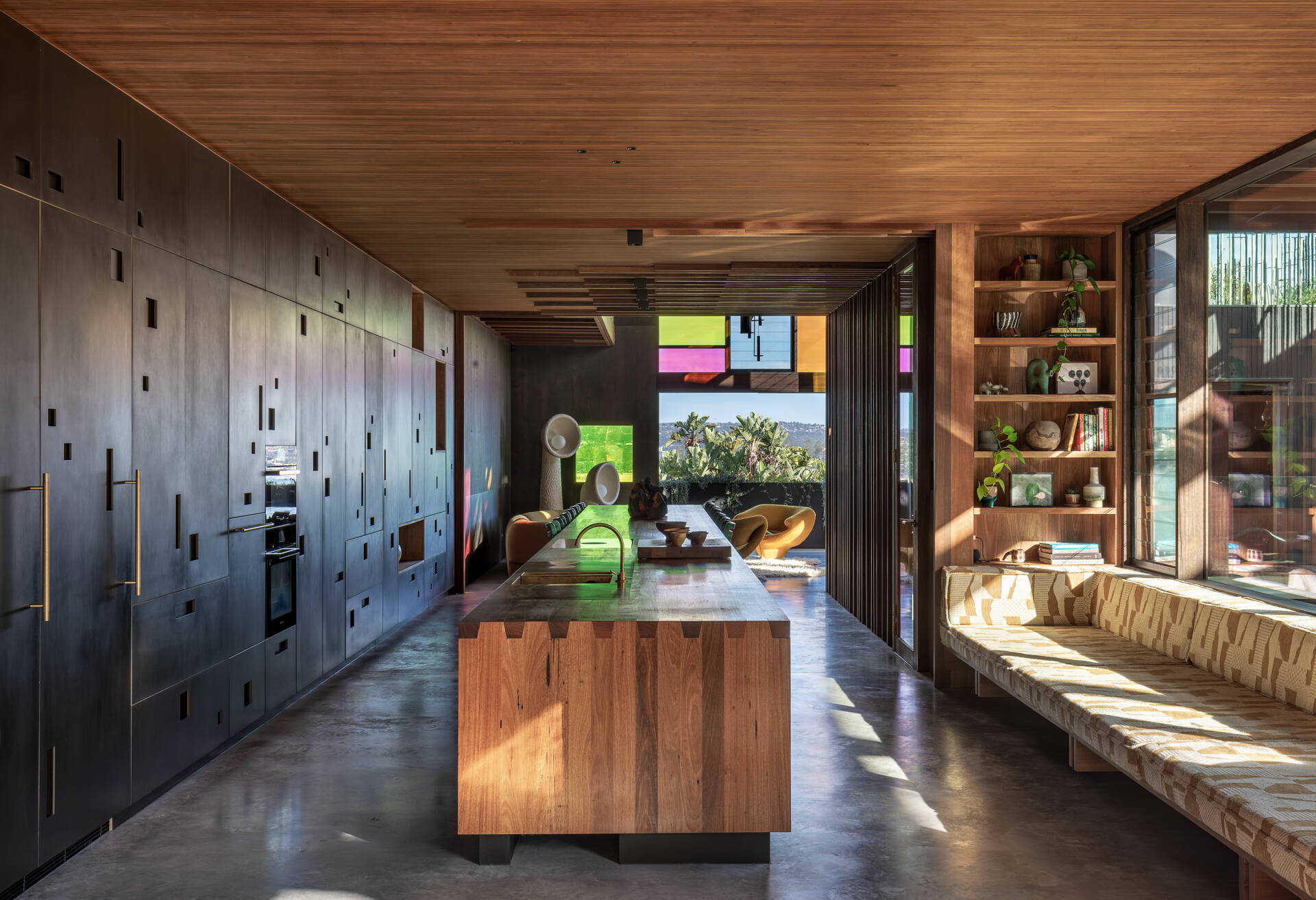 A 9.2 metre recycled hardwood island, which doubles as the dining table, stretches through to the kitchen. A full wall of cabinetry made from Paperock creates small niches that mimic dappled forest light, and offers generous storage without visual clutter. 