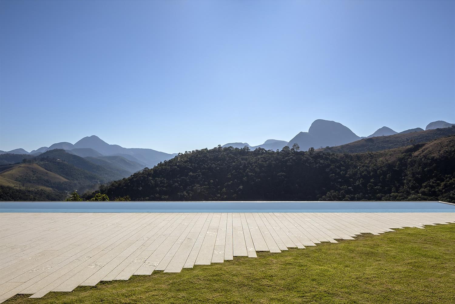 Casa Terra sits on a sloped mountain site in Itaipava, with patios and an infinity pool designed to fully embrace the surrounding views.