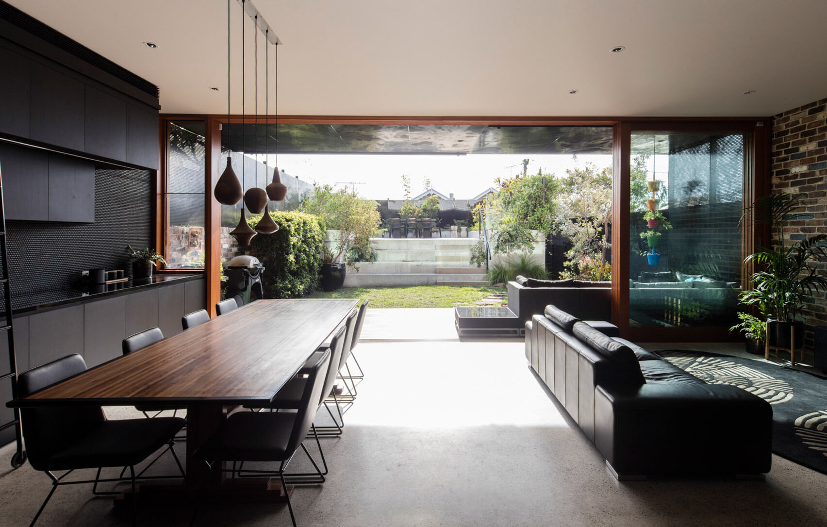 Full height sliding doors open the living and dining areas to a raised backyard dining zone filled with natural light.