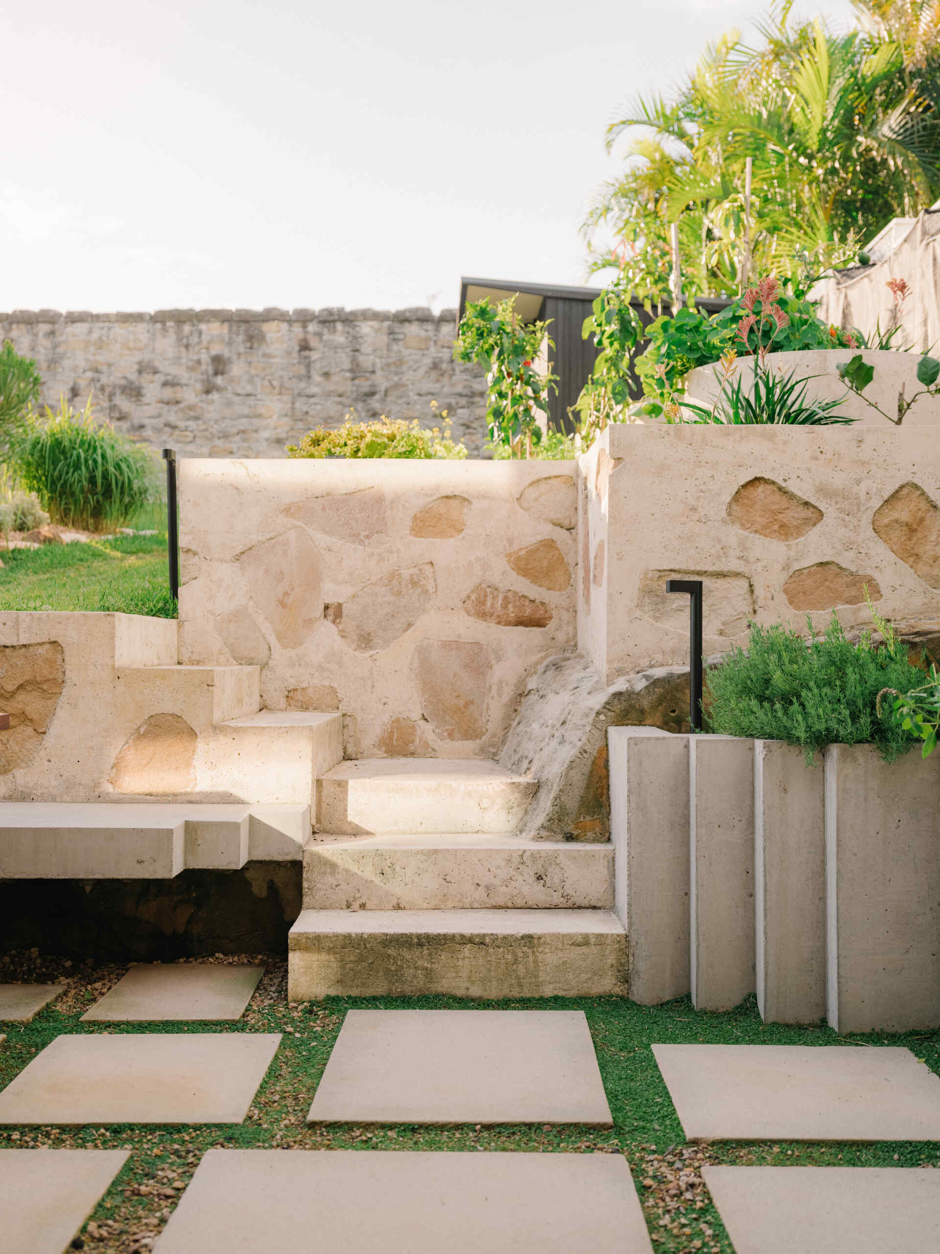 This garden supports self sufficiency with fruit trees, vegetables and herbs, while composting and mulching feed the soil, and food scraps support chickens. Rainwater and grey water systems irrigate the landscape. Outdoor dining areas sit within this productive garden, surrounded by plants selected to strengthen local ecology and support bandicoot habitat.
