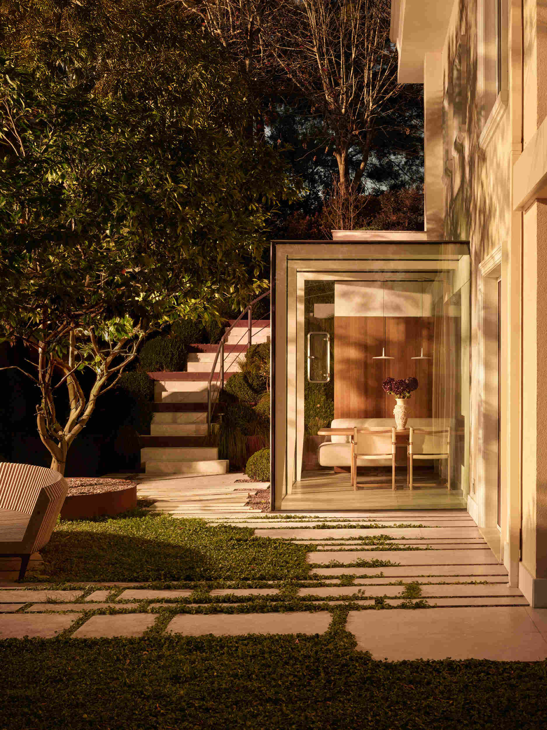 Garden stairs feel like a walk through a living sculpture. Pale stepping stones float over warm gravel, with tiered concrete steps rising between rust-colored planters. Ornamental grasses sway gently, and a slim metal handrail adds a modern line.