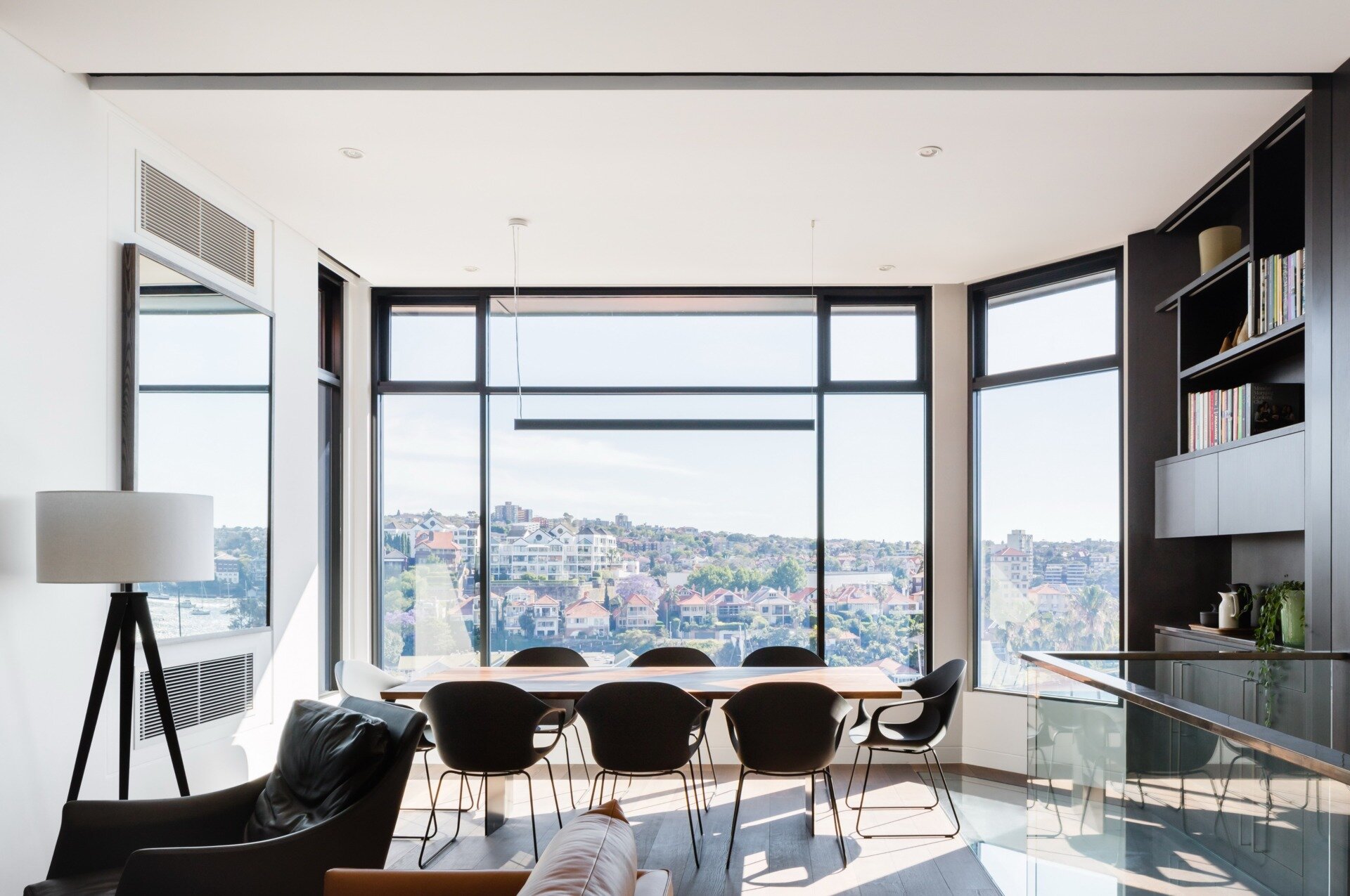 Steel beams and white walls frame a dining space designed to capture expansive harbour views.