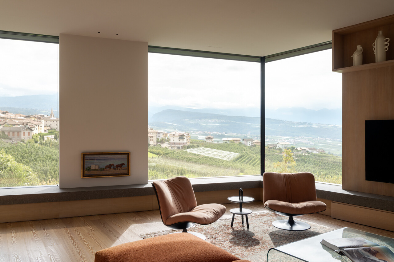 A sunken living room with lime plaster walls and a continuous stone windowsill creates a warm gathering space with panoramic views.