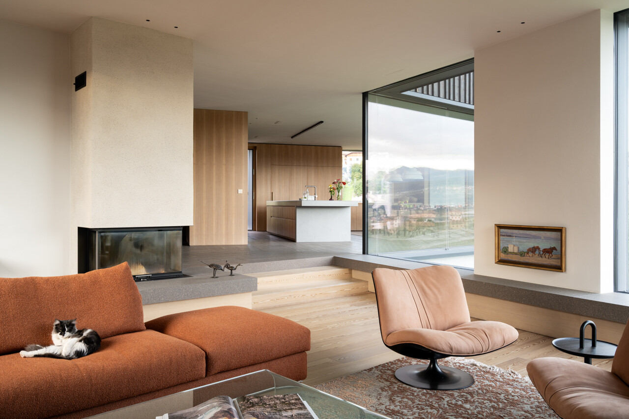 A sunken living room with lime plaster walls and a continuous stone windowsill creates a warm gathering space with panoramic views.