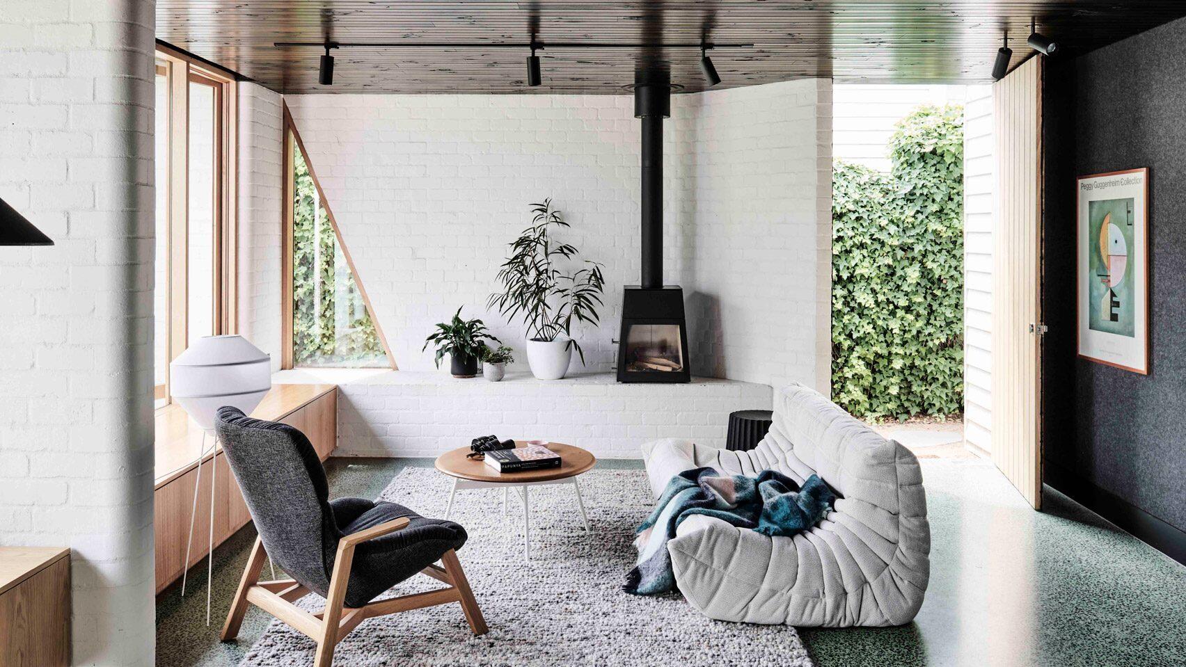 Bright white brick and warm wood create a cosy modern living room with sculptural walls and soft corners.