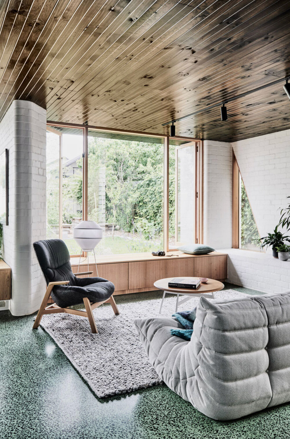 Bright white brick and warm wood create a cosy modern living room with sculptural walls and soft corners.