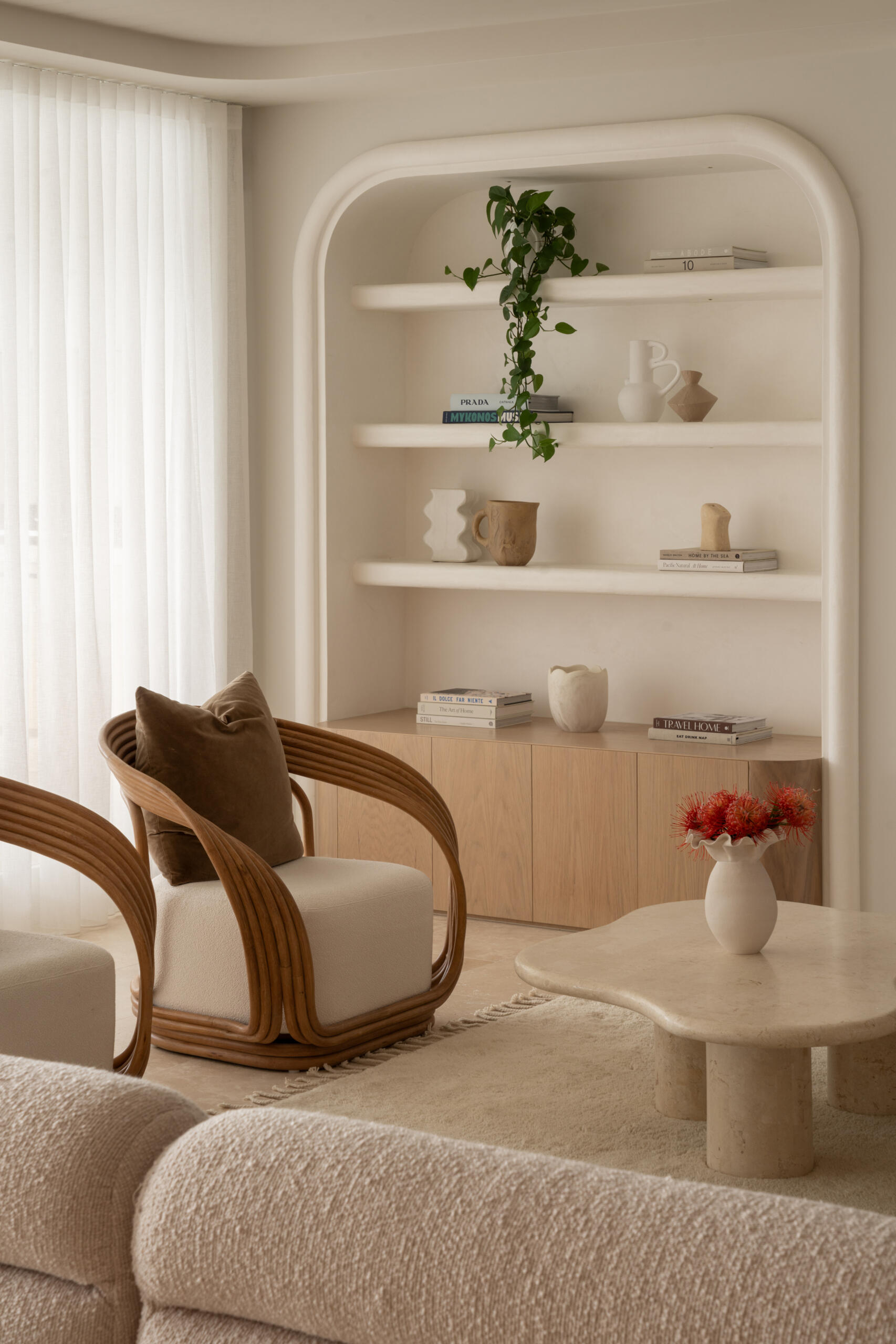 A warm living space with bullnose archways and a sculptural, cave-like wine cellar tucked into the wall.