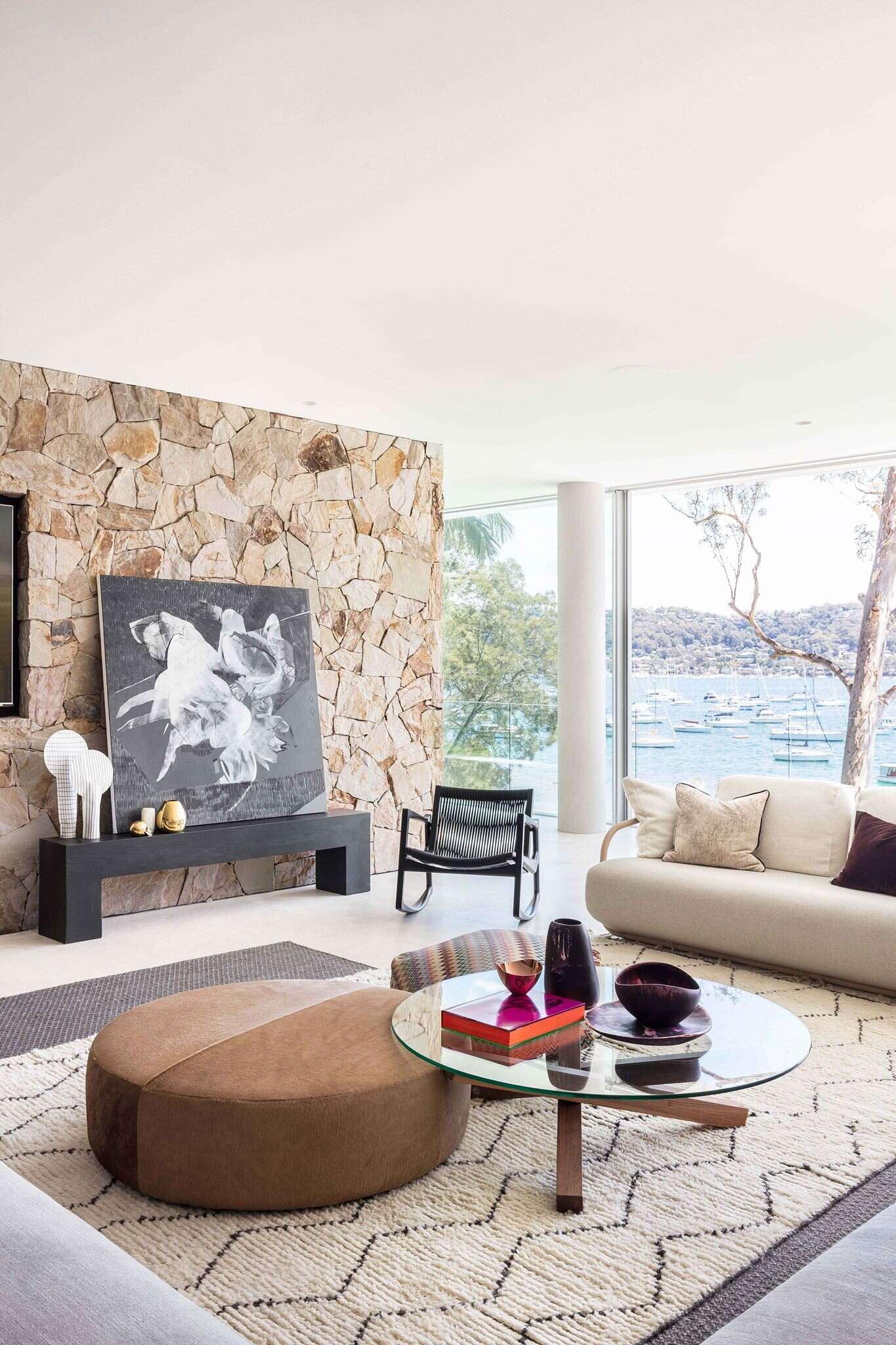 Stacked stone walls paired with full height glass create a calm, natural interior that keeps the focus on landscape and light.