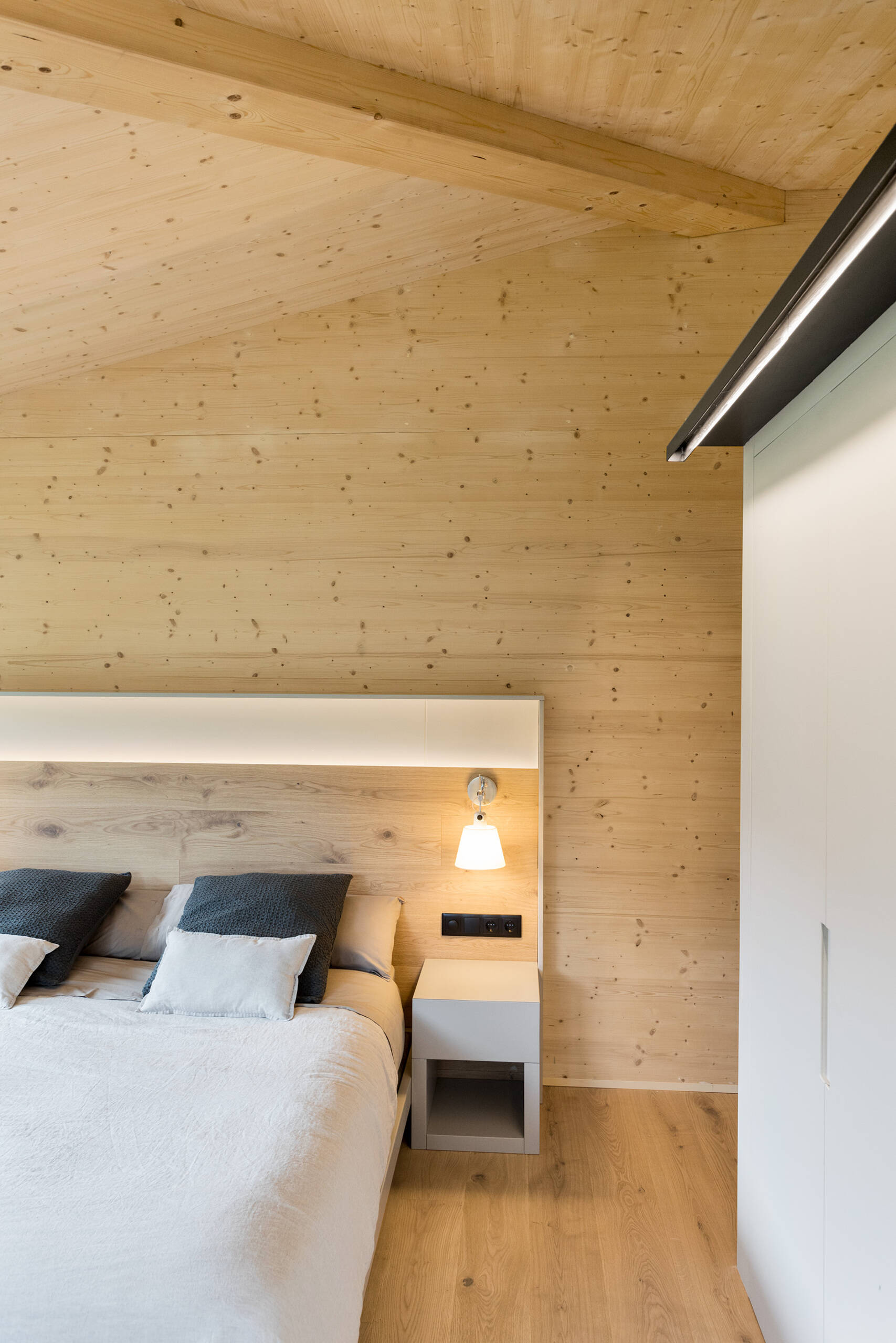 At the end of the hallway, the primary bedroom enjoys a sense of quiet separation. High ceilings enhance the feeling of space, while the consistent use of wood maintains the home’s cohesive interior language.