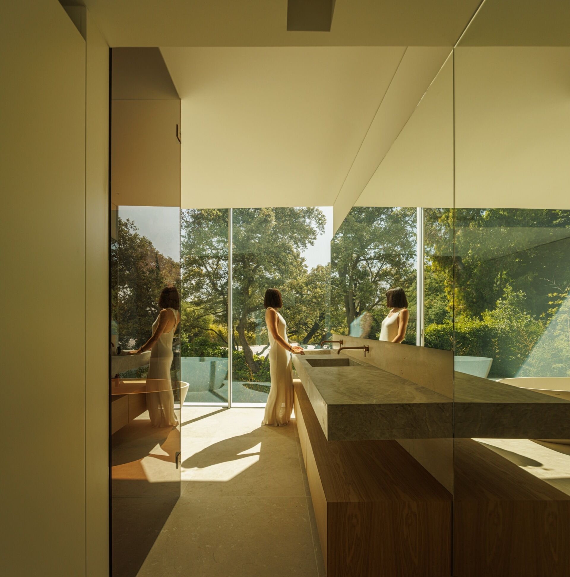 A modern bathroom with large windows that look out onto the garden.