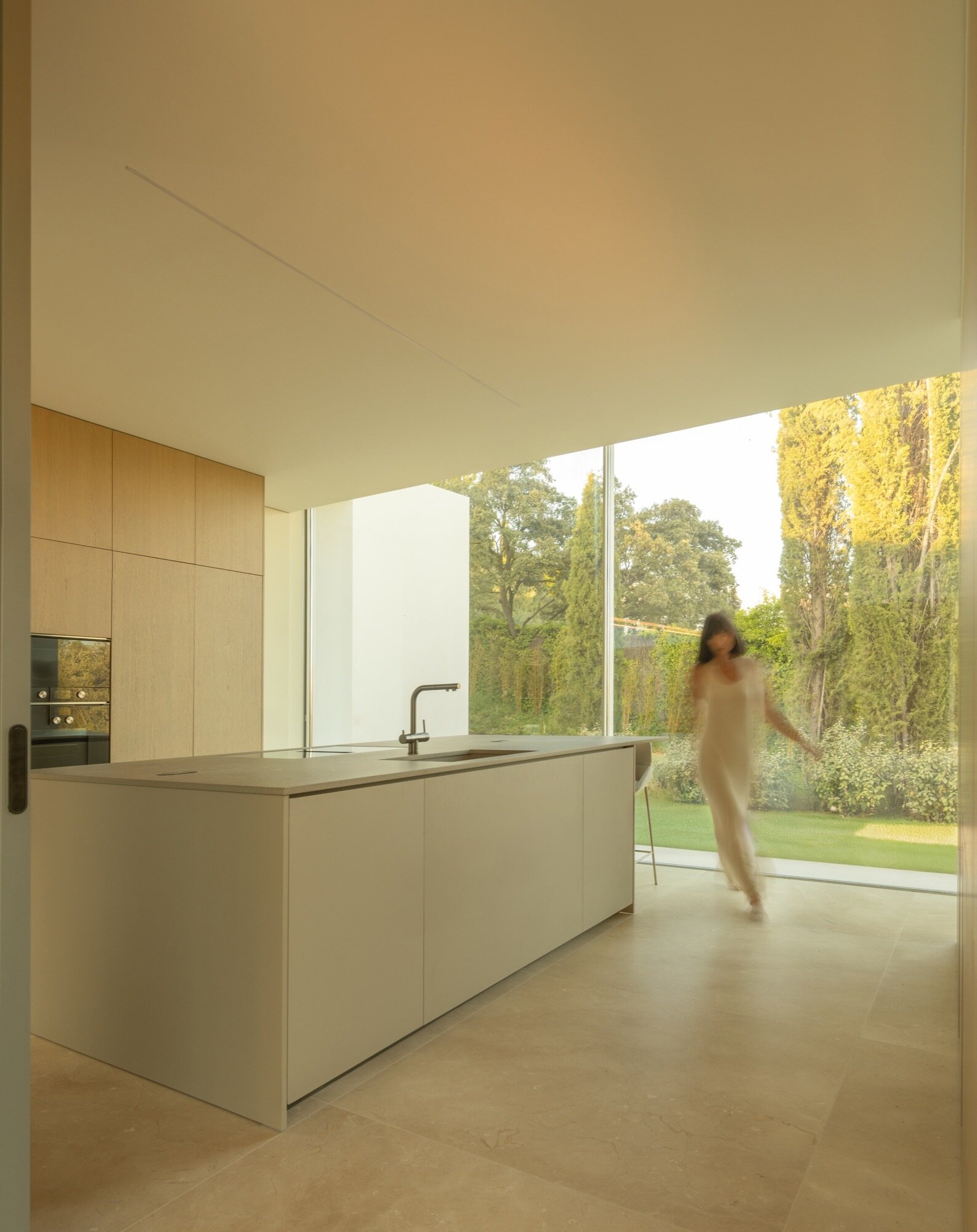 A minimalist kitchen with a large island and oversized windows.