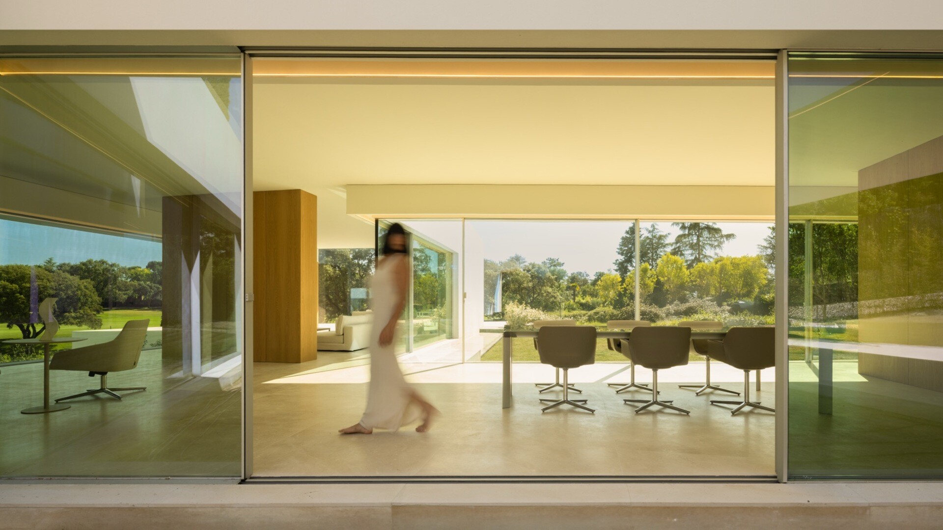 A minimalist dining room with sliding glass walls that connect to the outdoors.