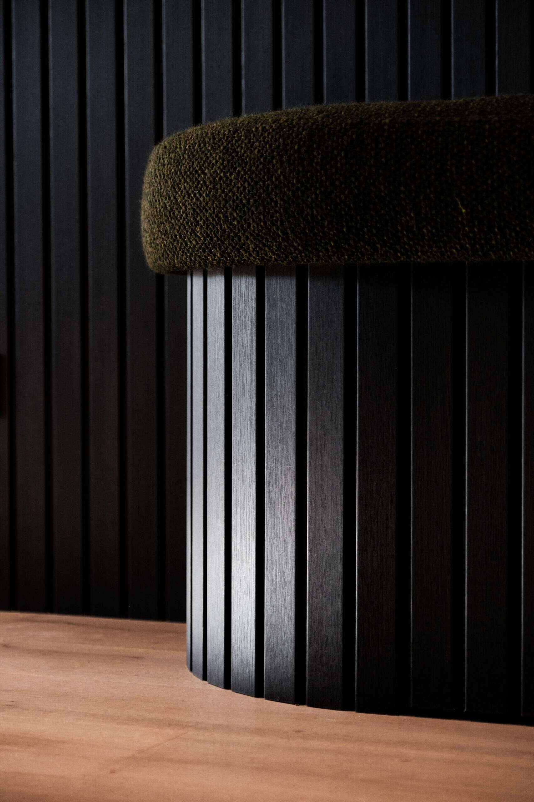A welcoming entryway with custom joinery, a built in bench and textured black wall panelling that sets the tone for the home.
