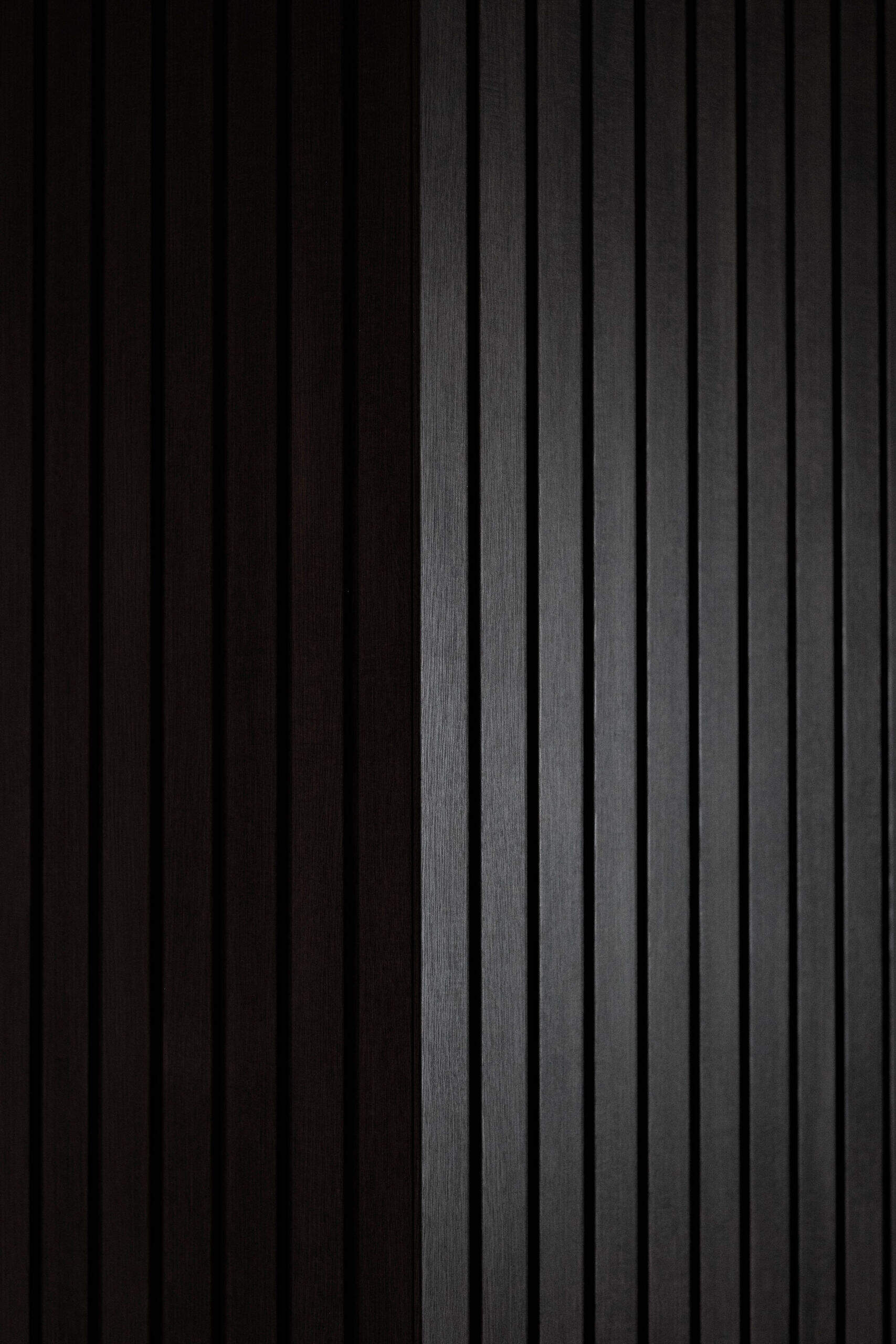 A welcoming entryway with custom joinery, a built in bench and textured black wall panelling that sets the tone for the home.