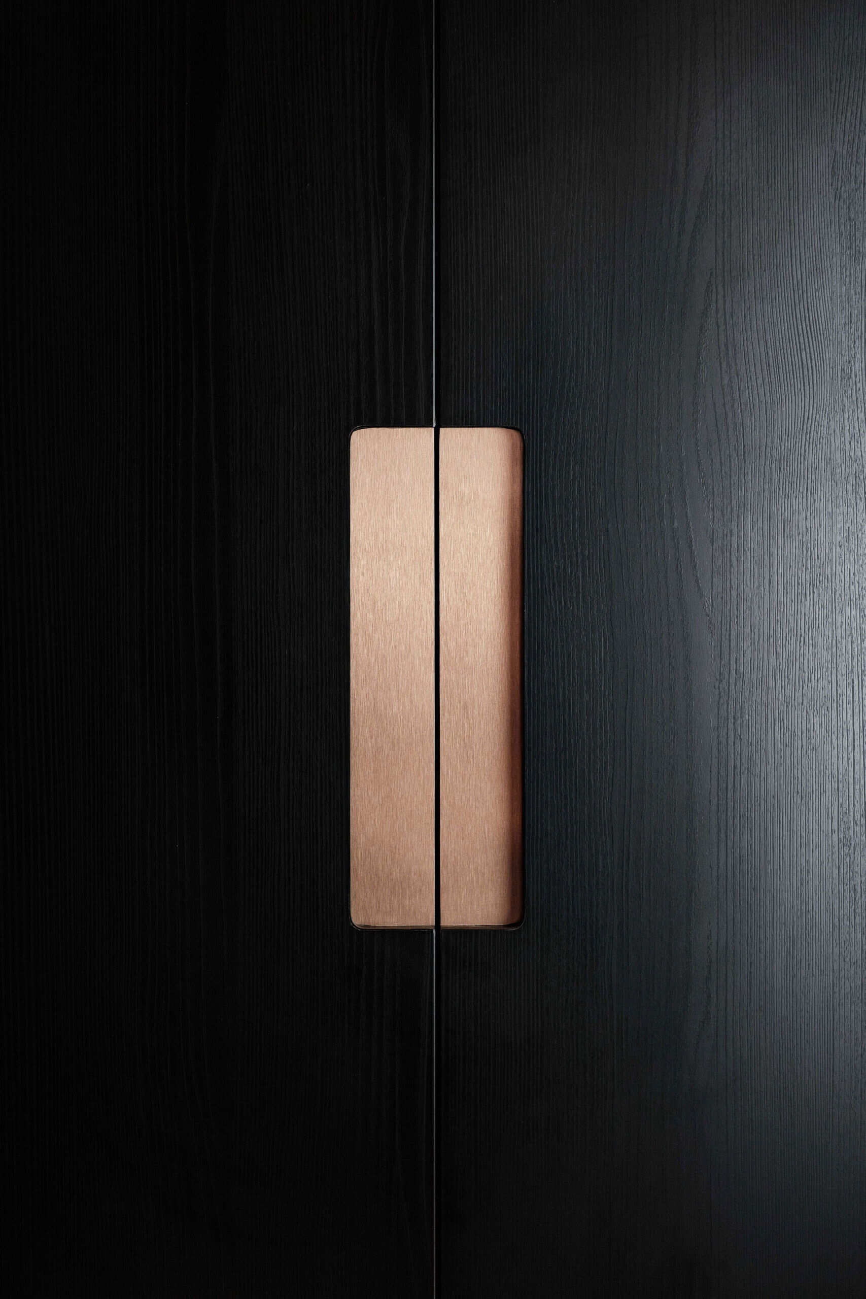 A welcoming entryway with custom joinery, a built in bench and textured black wall panelling that sets the tone for the home.