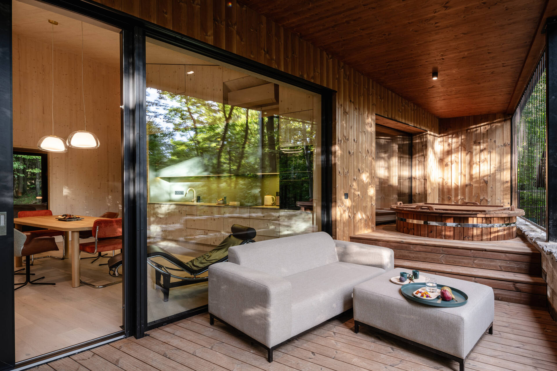A covered terrace wraps around the house, and includes an outdoor electric hot tub, lounge area, dining area, and the fireplace. There's also an open terrace that connects to this space, and together they all extend daily living into the forest.