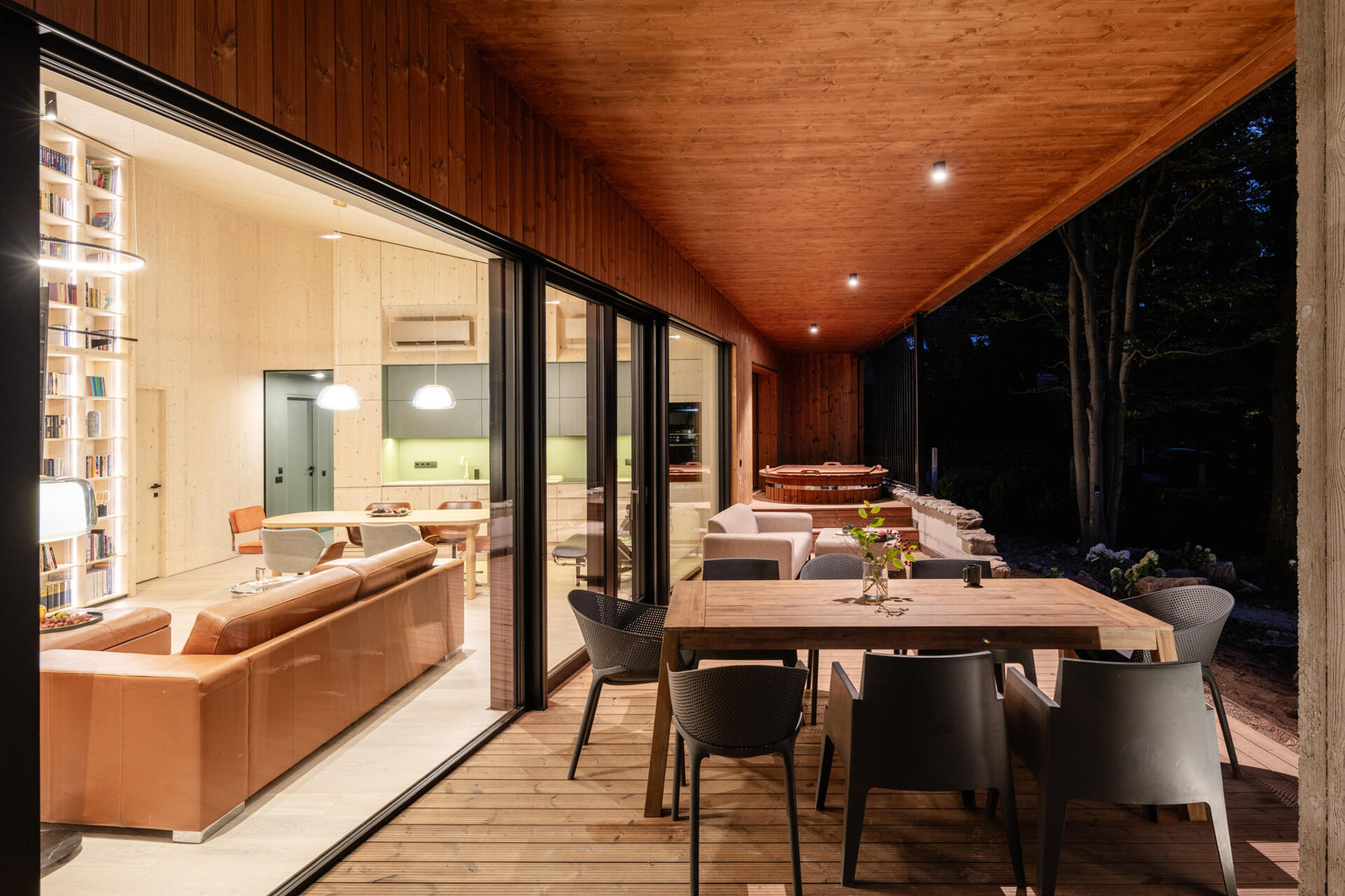 A covered terrace wraps around the house, and includes an outdoor electric hot tub, lounge area, dining area, and the fireplace. There's also an open terrace that connects to this space, and together they all extend daily living into the forest.