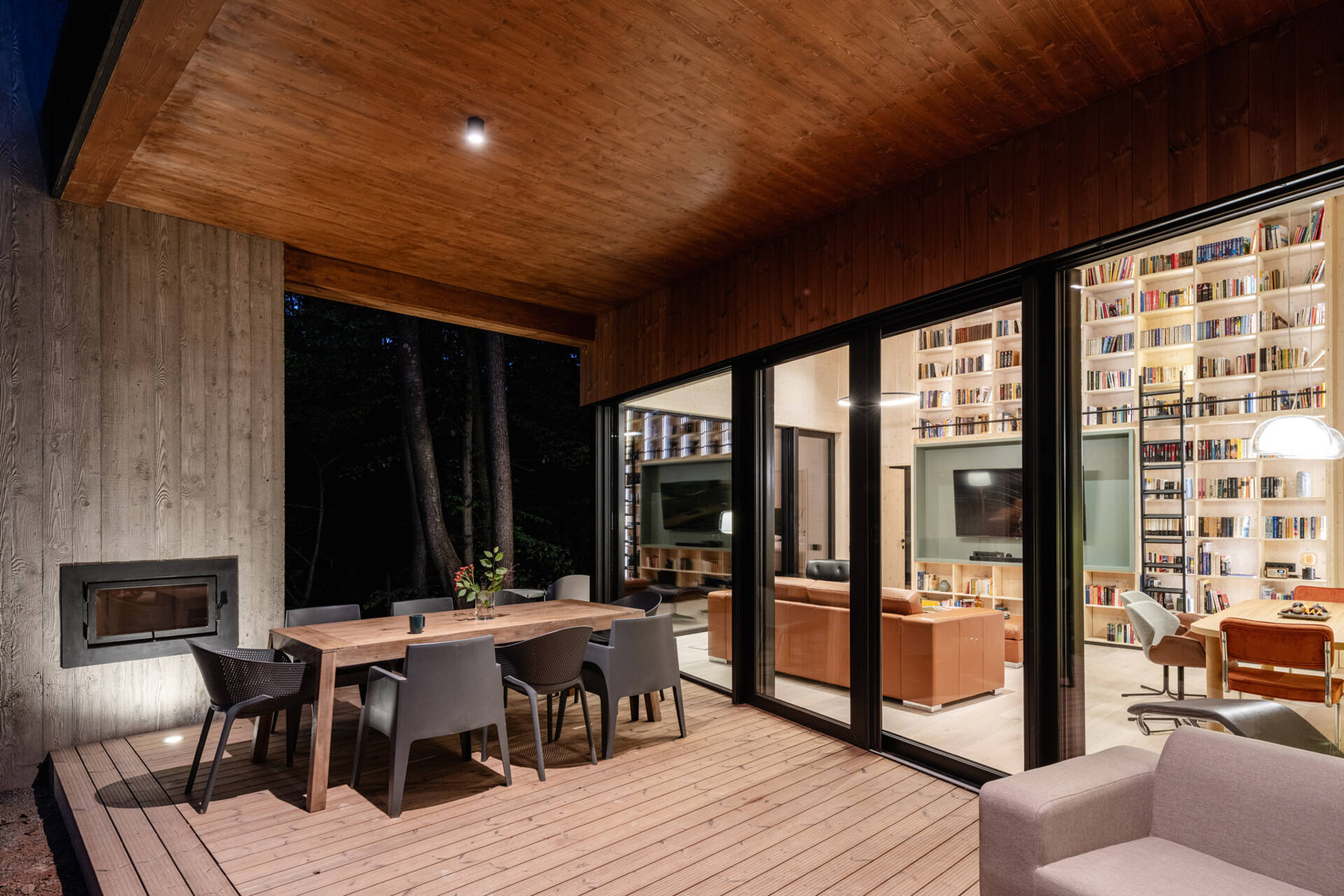 A covered terrace wraps around the house, and includes an outdoor electric hot tub, lounge area, dining area, and the fireplace. There's also an open terrace that connects to this space, and together they all extend daily living into the forest.