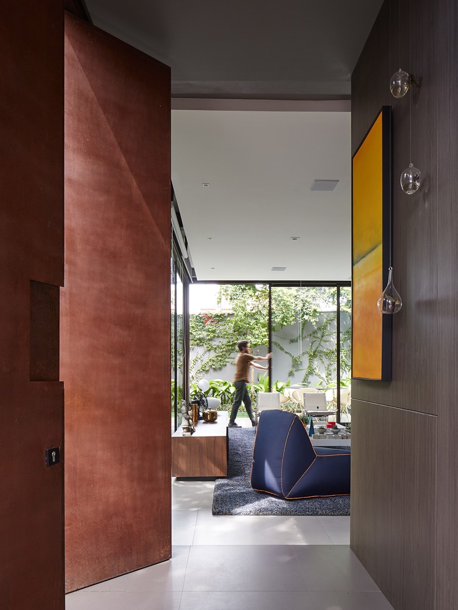 A weathering steel gate opens to a quiet garden entry, marking the transition from city street to private retreat.