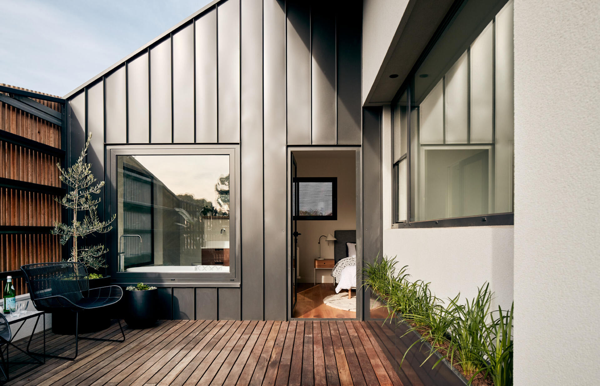 A plant-filled balcony sits behind a timber screen, offering privacy and a natural outlook.