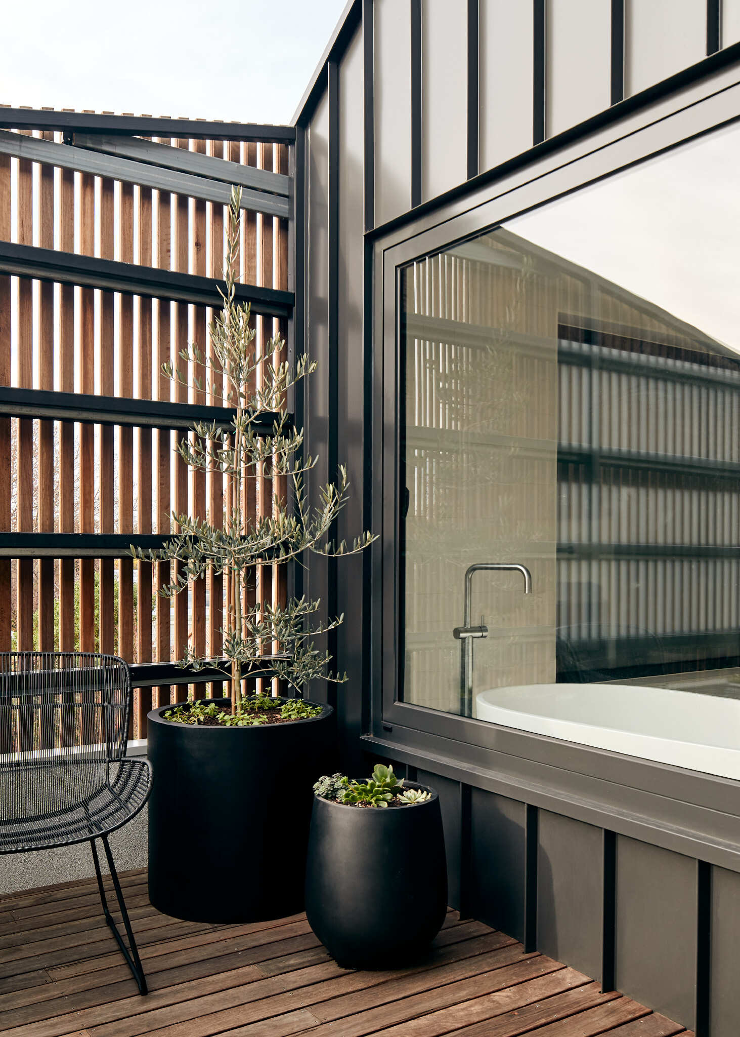 A plant-filled balcony sits behind a timber screen, offering privacy and a natural outlook.