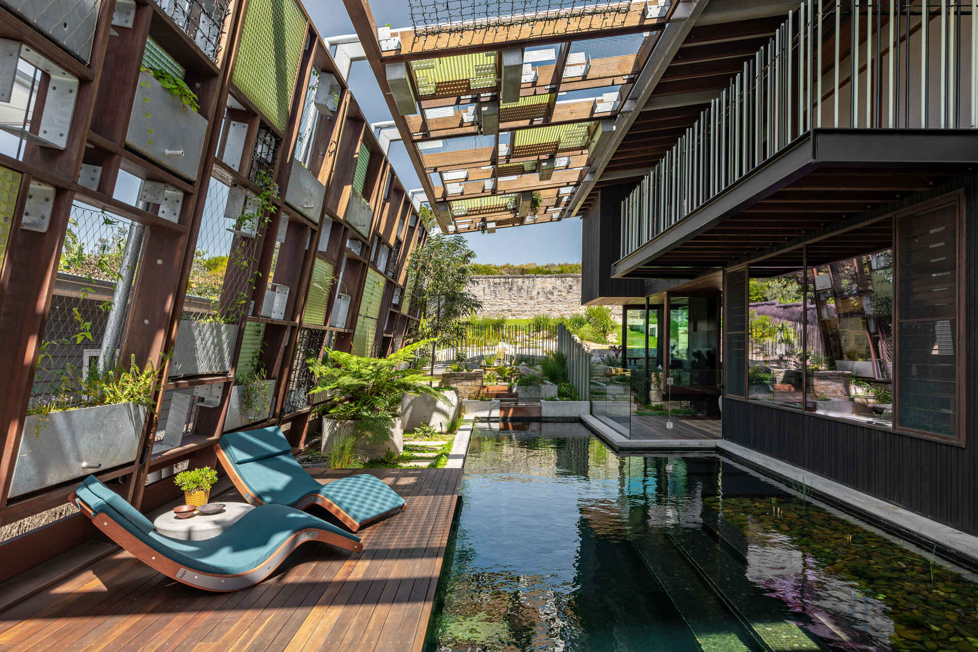 A natural swimming pool flows through the home beneath a canopy of plants and translucent FRP latticework.