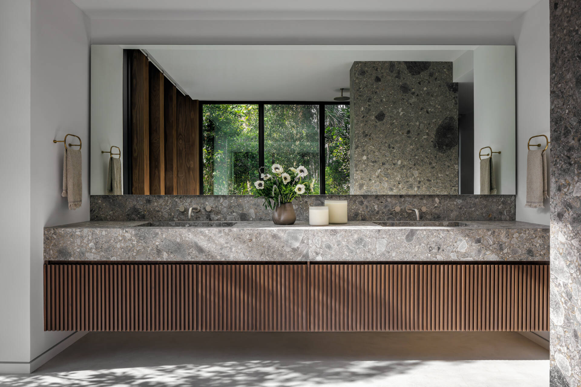 Terrazzo, warm wood, a soaking tub, and a walk-in shower frame garden views, creating a calm and uncluttered bathroom retreat.
