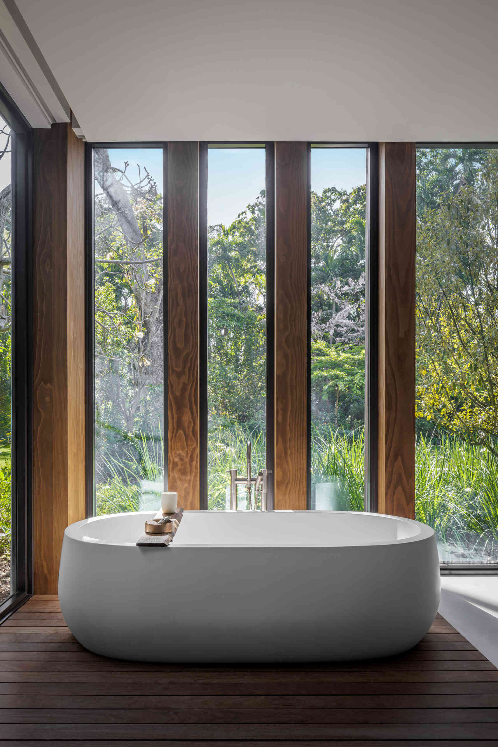 Terrazzo, warm wood, a soaking tub, and a walk-in shower frame garden views, creating a calm and uncluttered bathroom retreat.