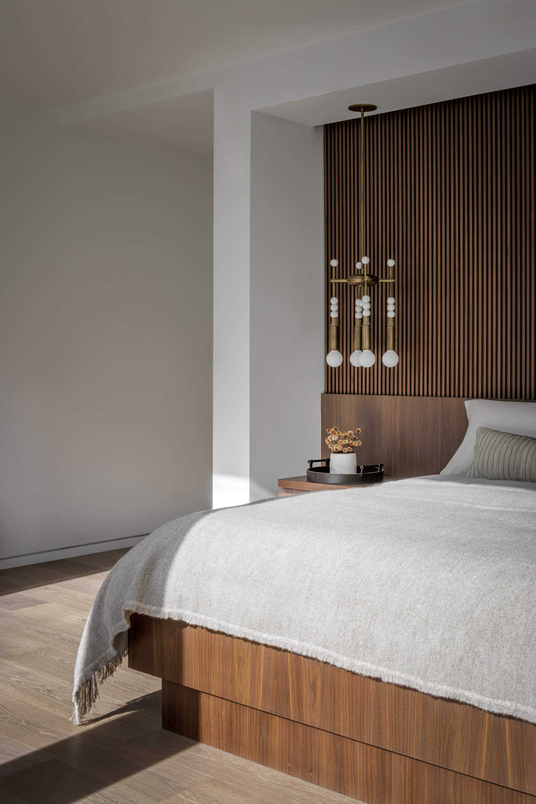 Warm wood and soft neutrals create a serene bedroom filled with morning light and a quiet, inviting atmosphere.