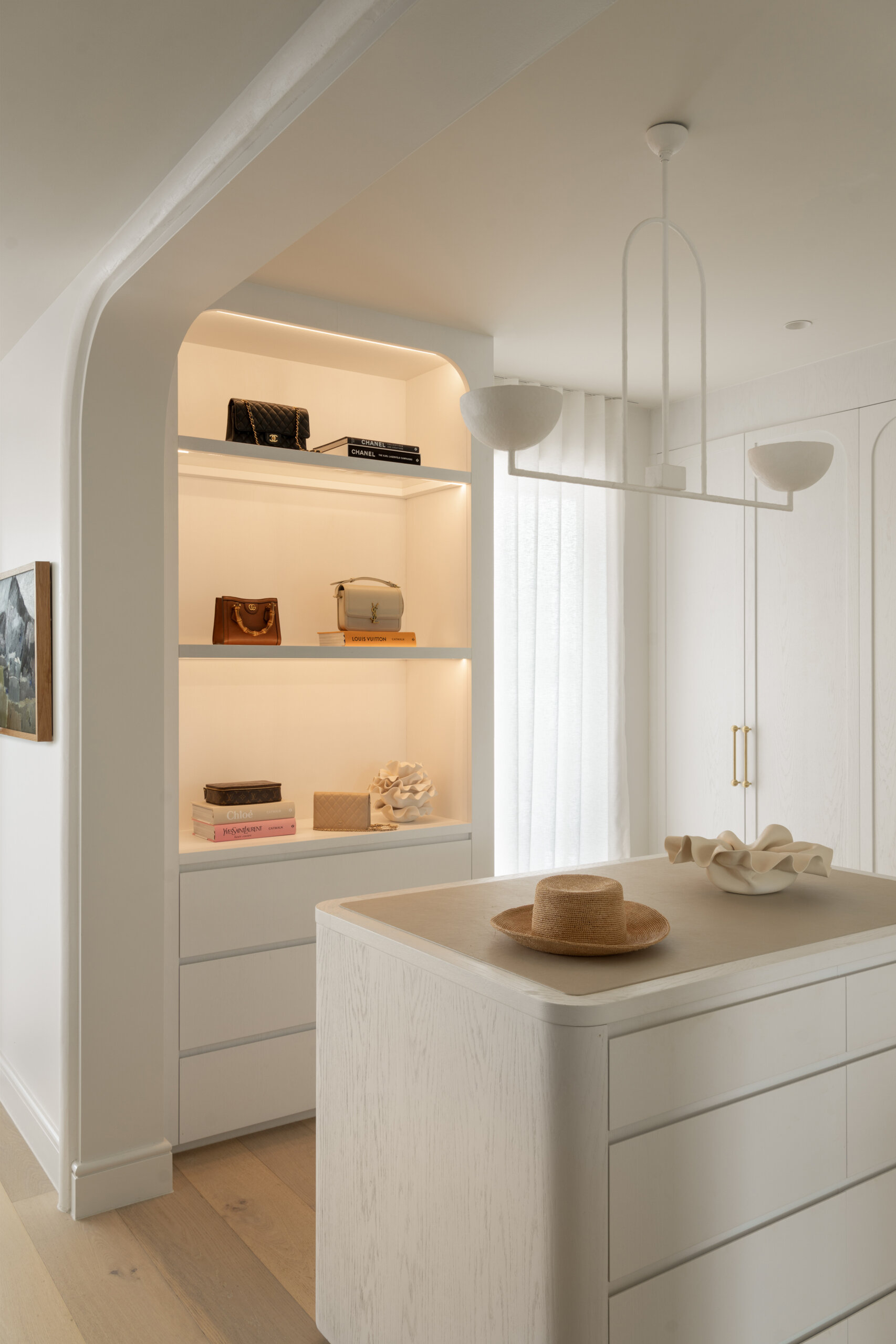 The primary suite is designed for unwinding. The bedroom stays understated and layered, with a calm presence that settles instantly. In the walk-in robe, a clean white scheme comes to life with warm lighting bouncing off subtle timber grain.