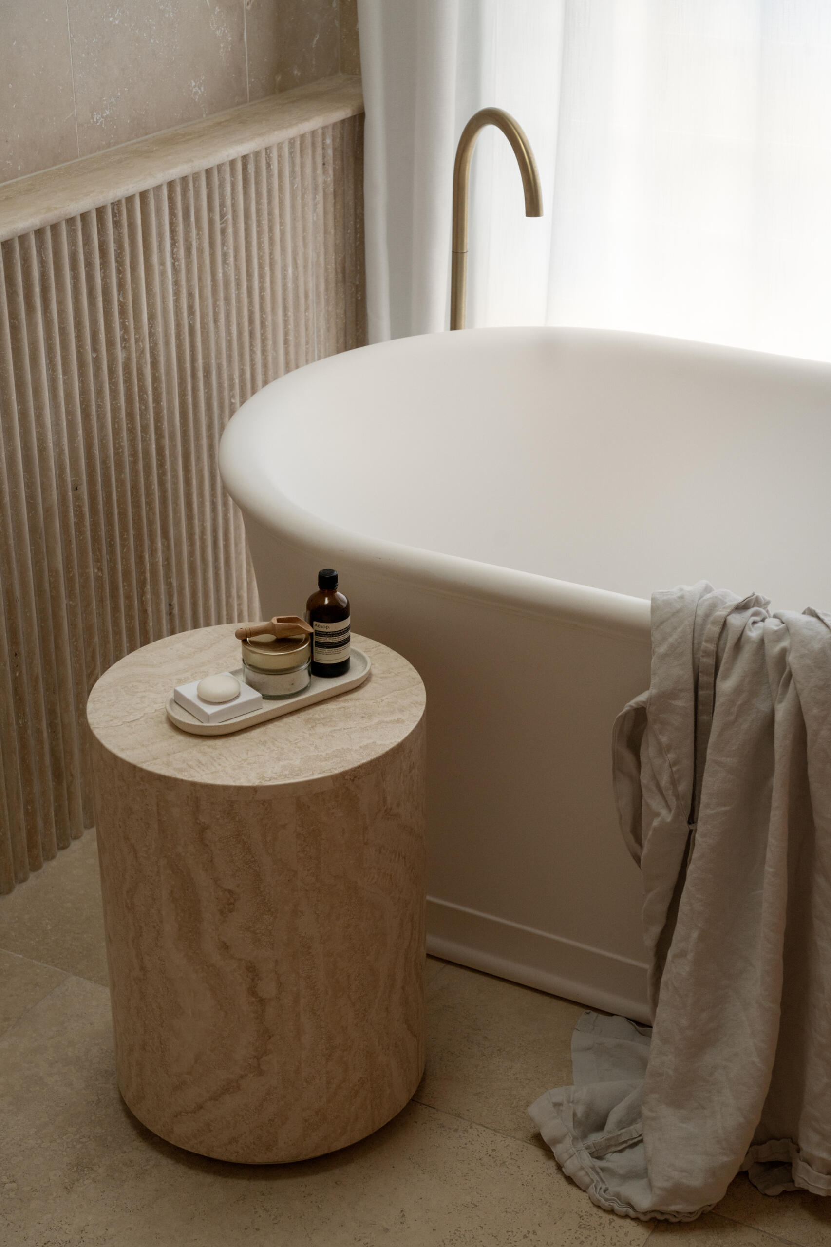 This en-suite bathroom turns the softer notes up a little further, using fluted stone with rounded edges to create visual interest while maintaining the spa-like serenity. Travertine remains the hero, divided into zones to give the space a sense of layered grandeur.