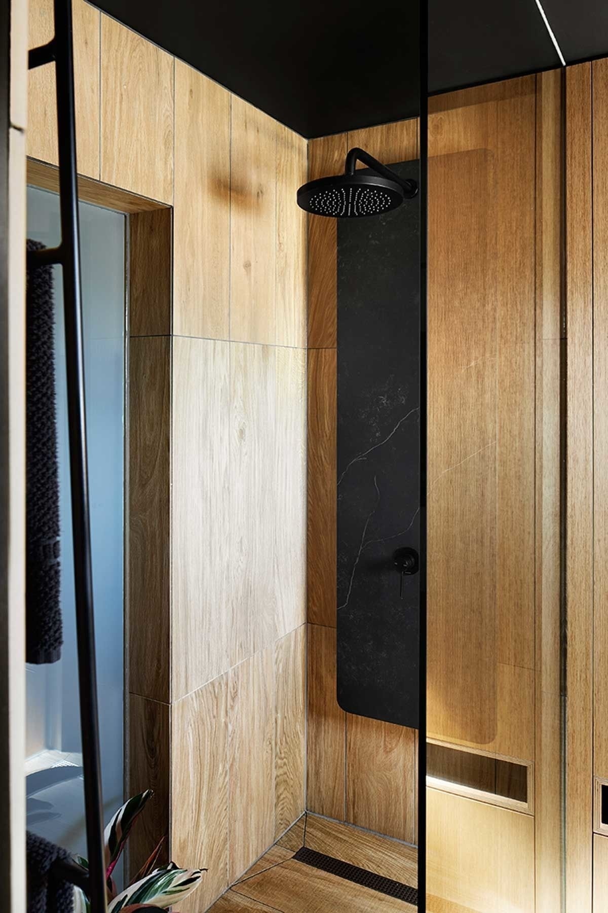 Timber-look tiles, a green wall and hidden drying line turn this compact bathroom into a calm, functional retreat.
