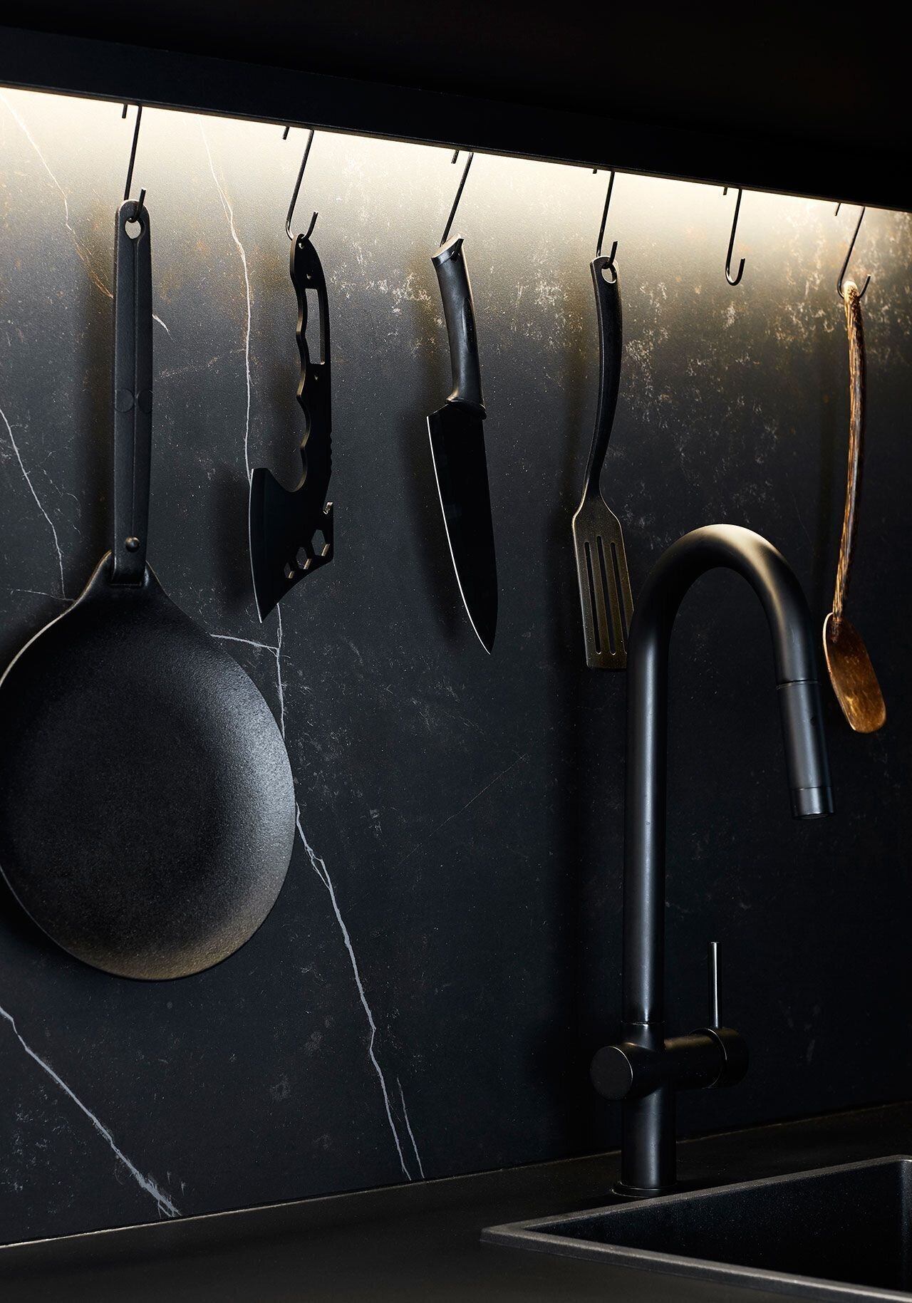 A long timber kitchen with black accents hides appliances and maximises bench space inside this compact Melbourne apartment.