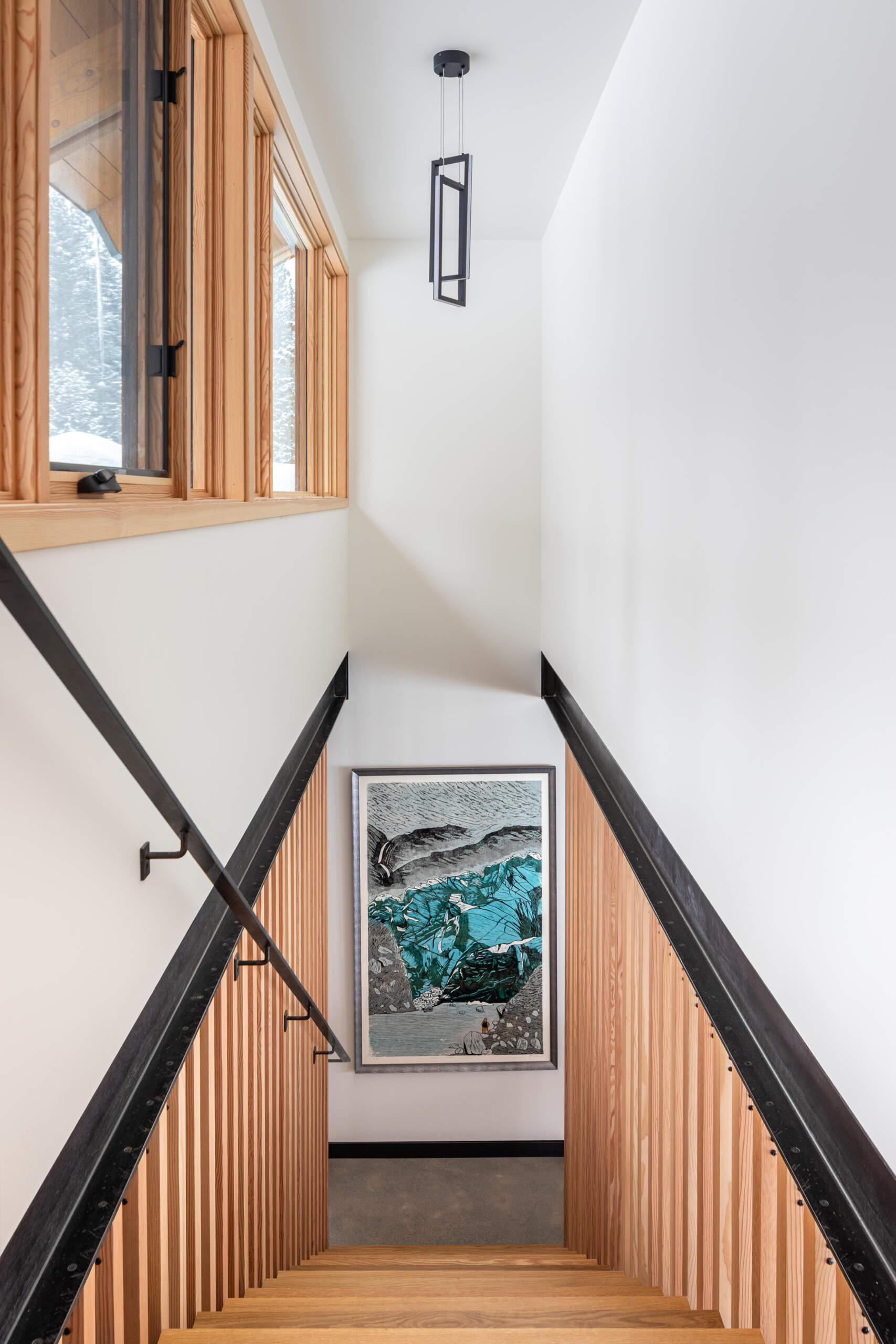 A sculptural stairway with black steel treads and a vertical wood slat screen, allowing light to move freely while adding texture and architectural interest.