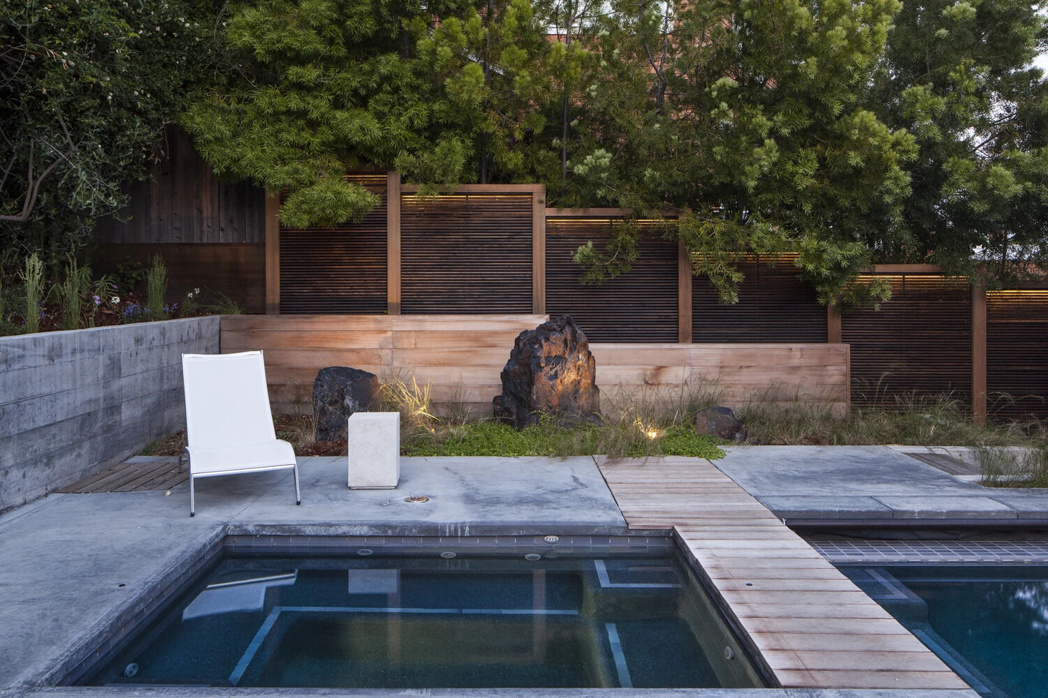 A wooden walkway connects the pool and spa, creating a seamless flow through the backyard.
