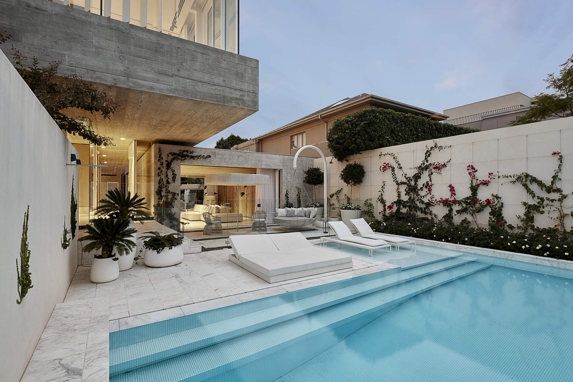A marble tiled pool courtyard uses greenery and an all white palette to create a private inner city oasis.