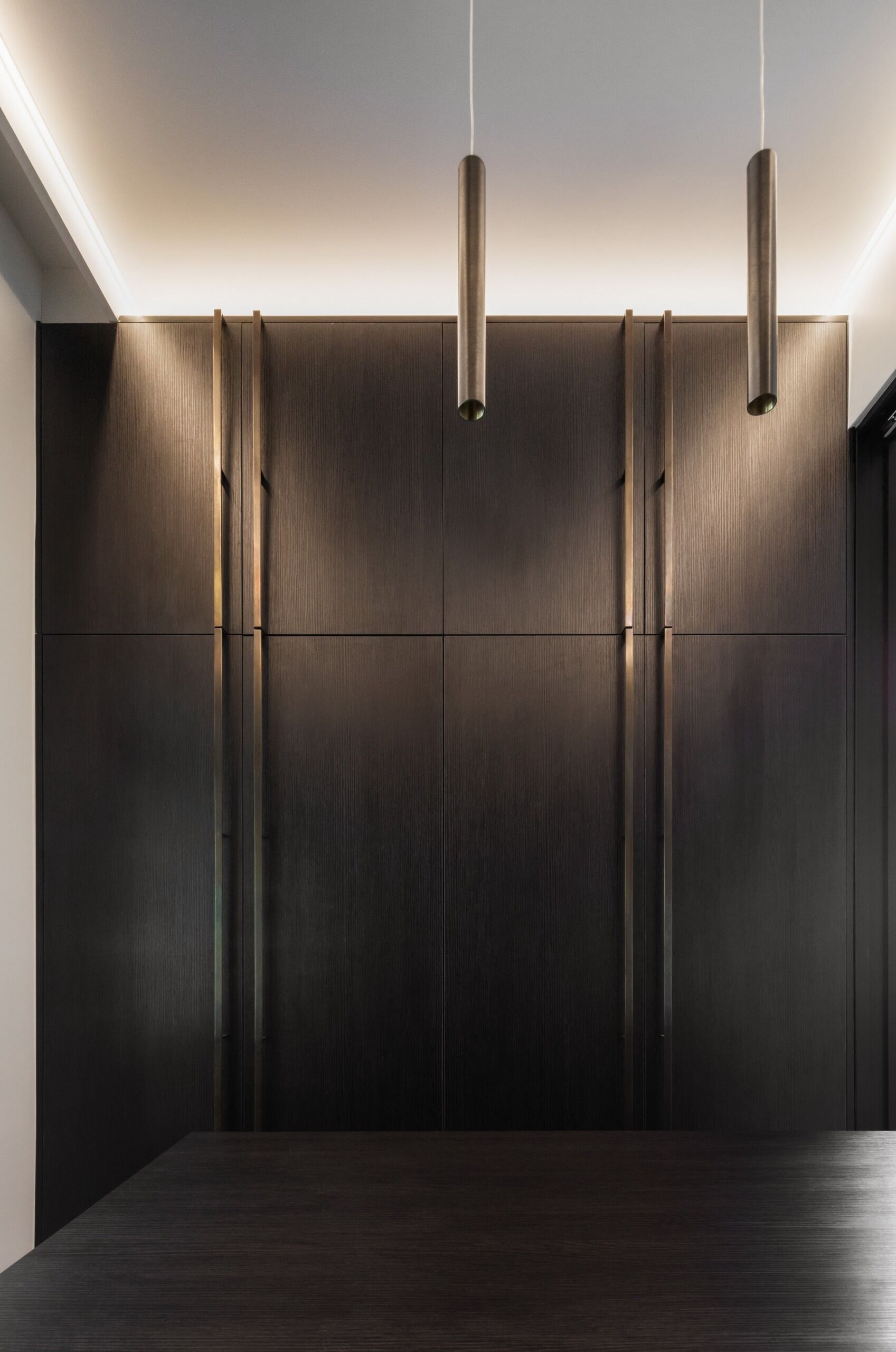 Dark cabinetry and bronze hardware give the walk in closet a rich, considered finish.
