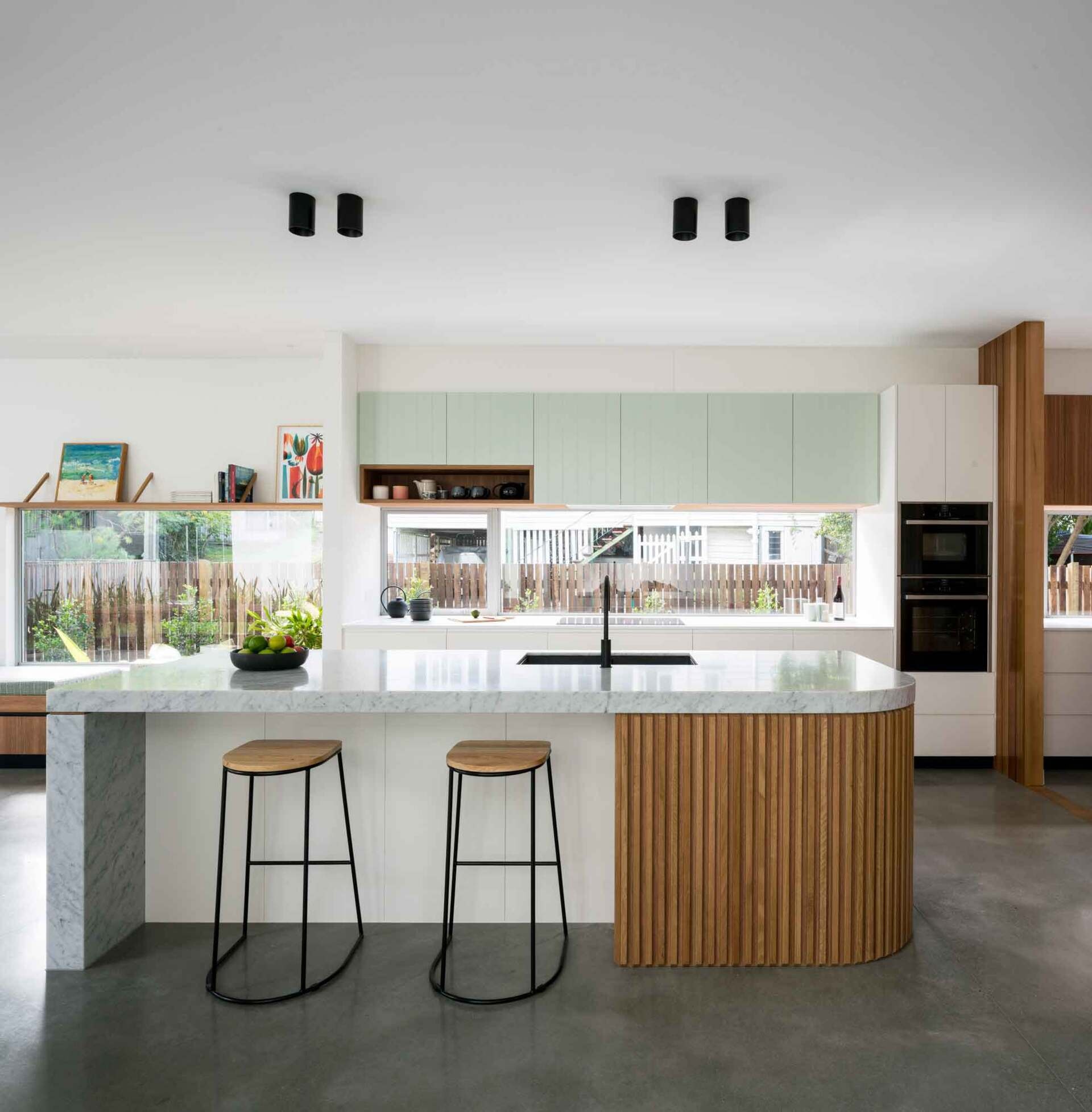 Clean cabinetry and a curved kitchen island create a calm, modern kitchen with mid-century influence.